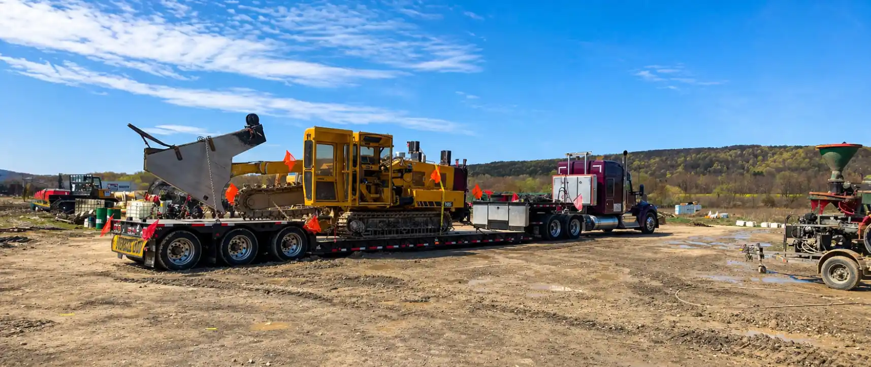 Maquinaria de construcción sobredimensionada transportada en un remolque de plataforma en un sitio de obra