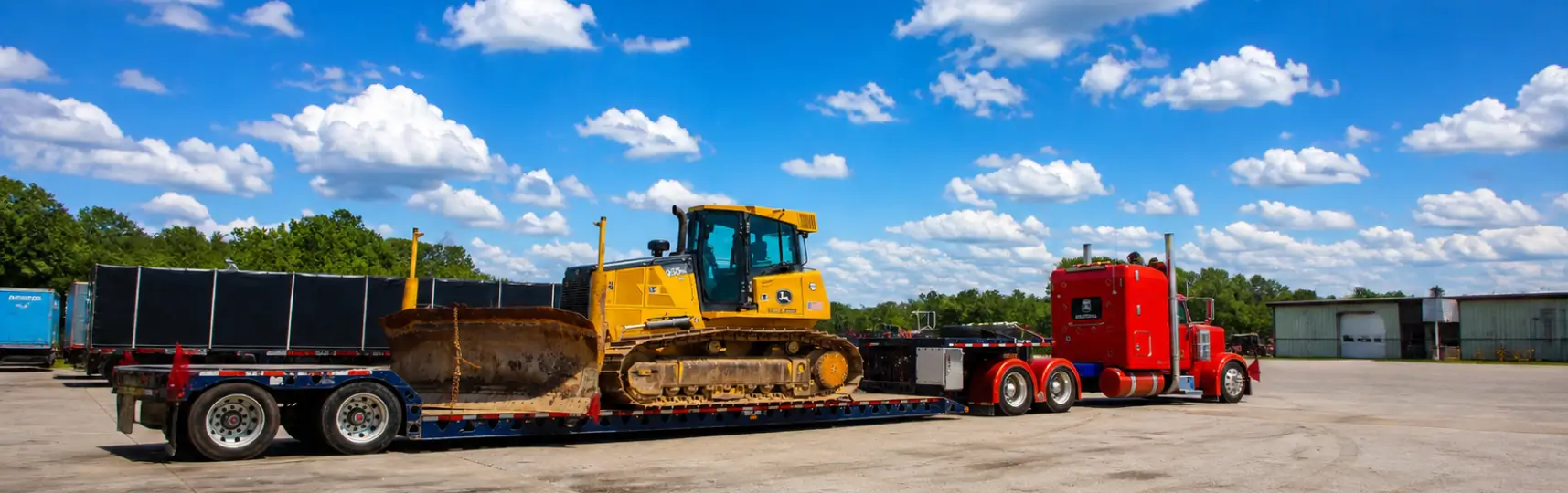 Heavy haul truck transporting a bulldozer on a lowboy trailer at an industrial site